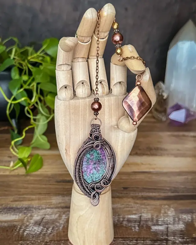 A pendulum of contrast and harmony—fiery ruby dances within earthy zoisite, inviting you to trust your instincts while grounding your insights in truth.This elegantly wire-wrapped pendulum blends the grounding energy of zoisite with the passion of ruby. A striking piece for empowered divination.

✨ Magickal Benefits of Ruby Zoisite ✨
- Balances passion and patience, blending the fiery energy of ruby with the stabilizing force of zoisite.
- Enhances spiritual insight, aiding in deep meditation and intuitive work.
- Supports energy clearing, making it an ideal pendulum for space cleansing.
- Encourages transformation and growth, perfect for those embracing new beginnings.

✨ Uses & Versatility ✨
- Divination and dowsing for spiritual guidance
- Energy work and chakra balancing
- Clearing blockages and setting focused intentions
- Enhancing intuitive awareness and meditation

This and many other magickal creations available in the shop, link in bio.

#makingmagic #makingmagic #makeeverydaymagic #magicaltools #crystalenergy #divinationtools #ritualtools #witchylife #herenchantedcreations #everydaywitchcraft #everydaymagic #rubyzoisite